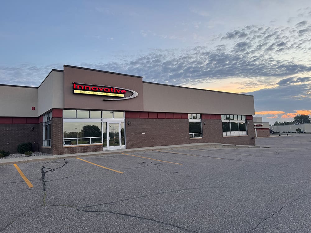 A mostly empty parking lot in front of a one-story commercial building with a sign reading 