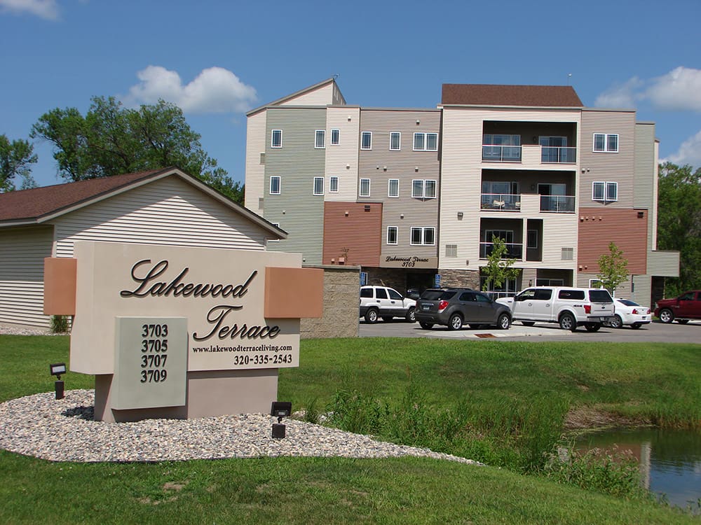 A modern apartment building with balconies stands behind a 